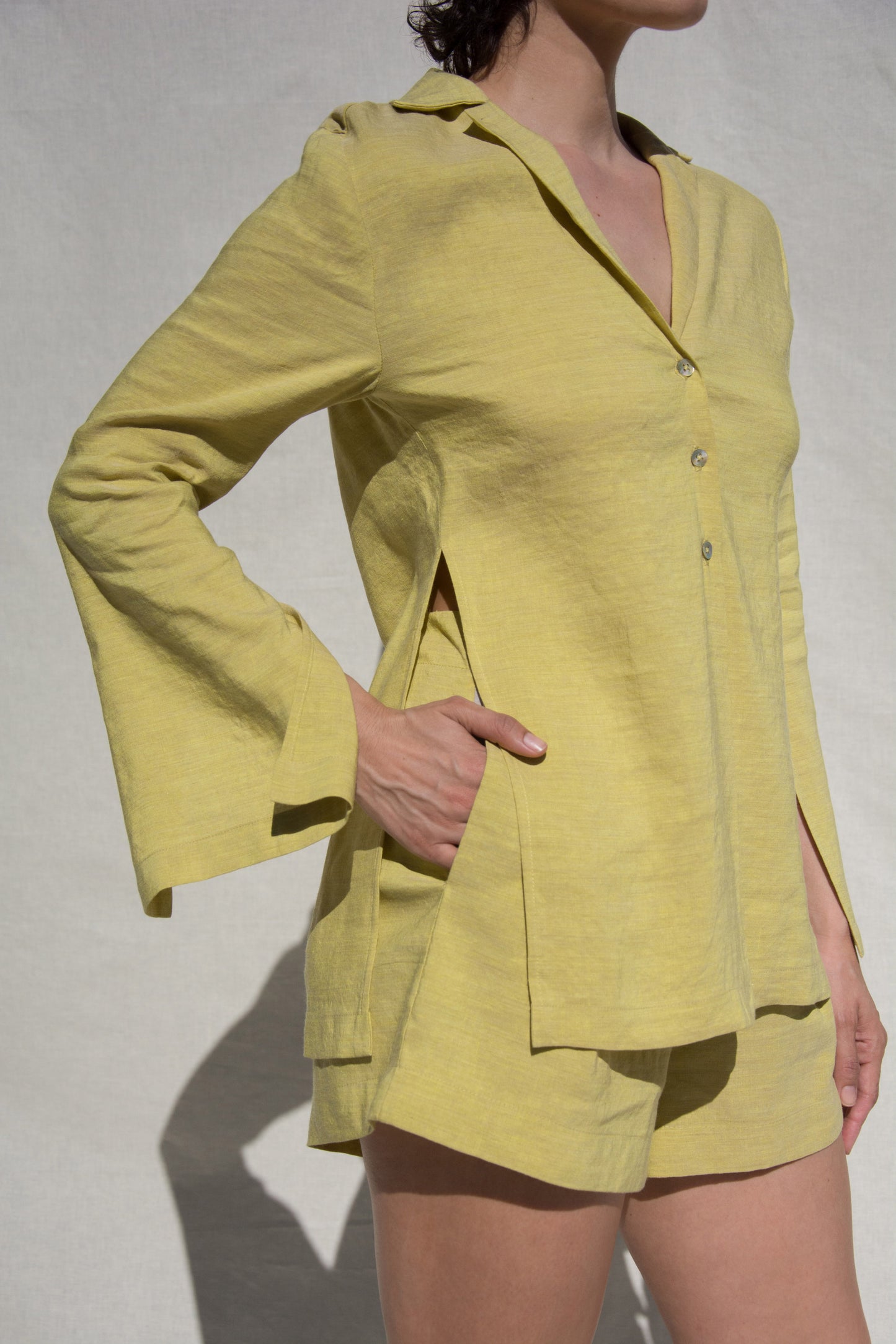 Side angle shot of model wearing long sleeve shirt and short set in Green Linen. Wearing Ceramic Pink earrings