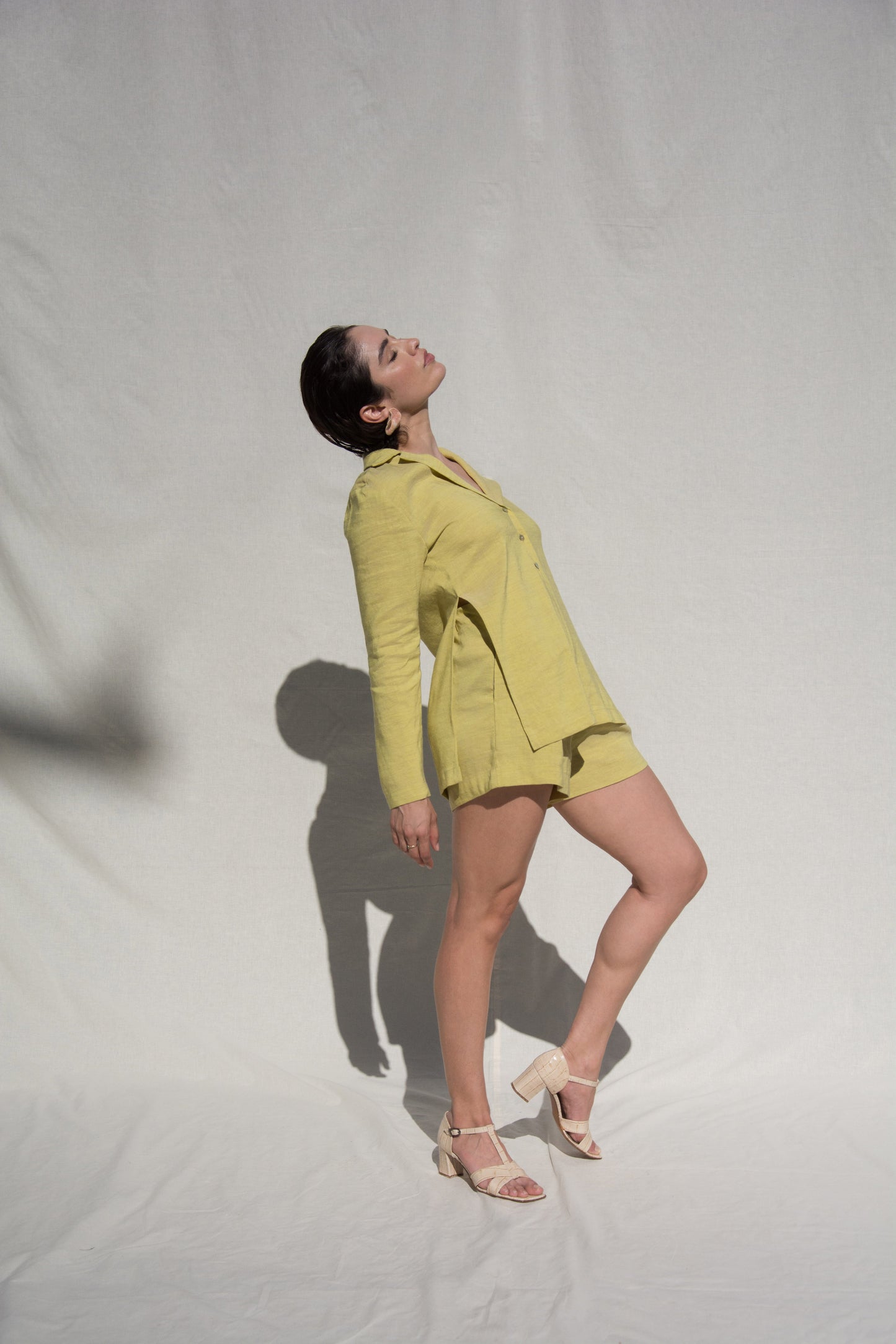 Side angle shot of model wearing long sleeve shirt and short set in Green Linen. Wearing Ceramic Pink earrings