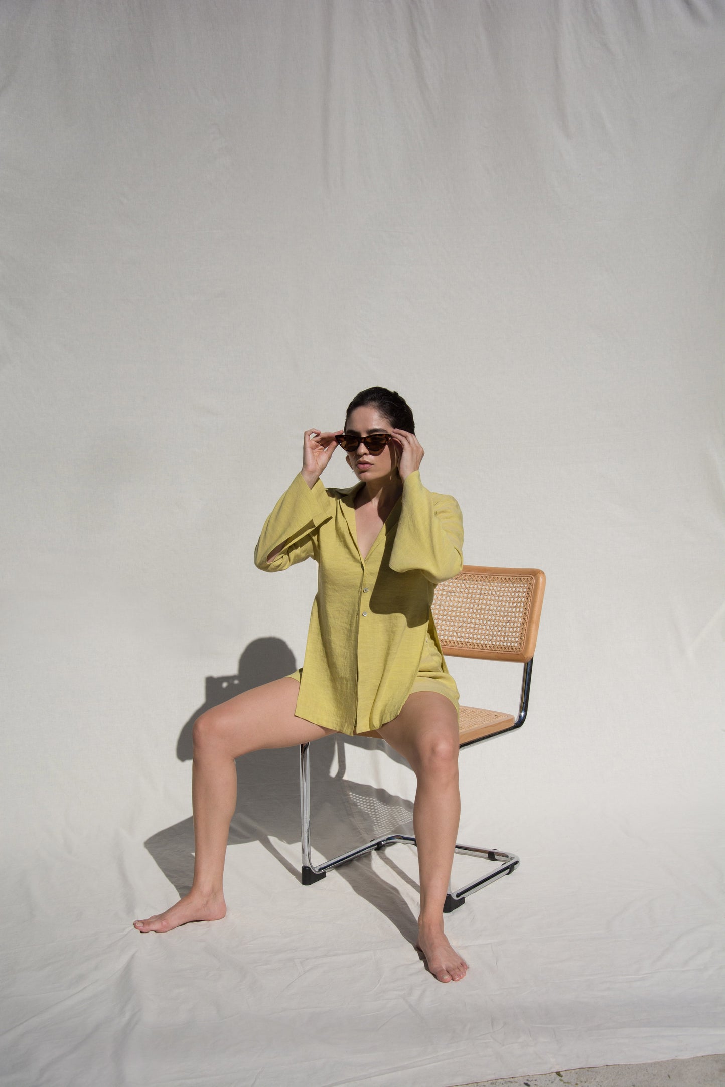 Front shot of model sitting wearing long sleeve shirt and short set in Green Linen. Wearing Ceramic Pink earrings
