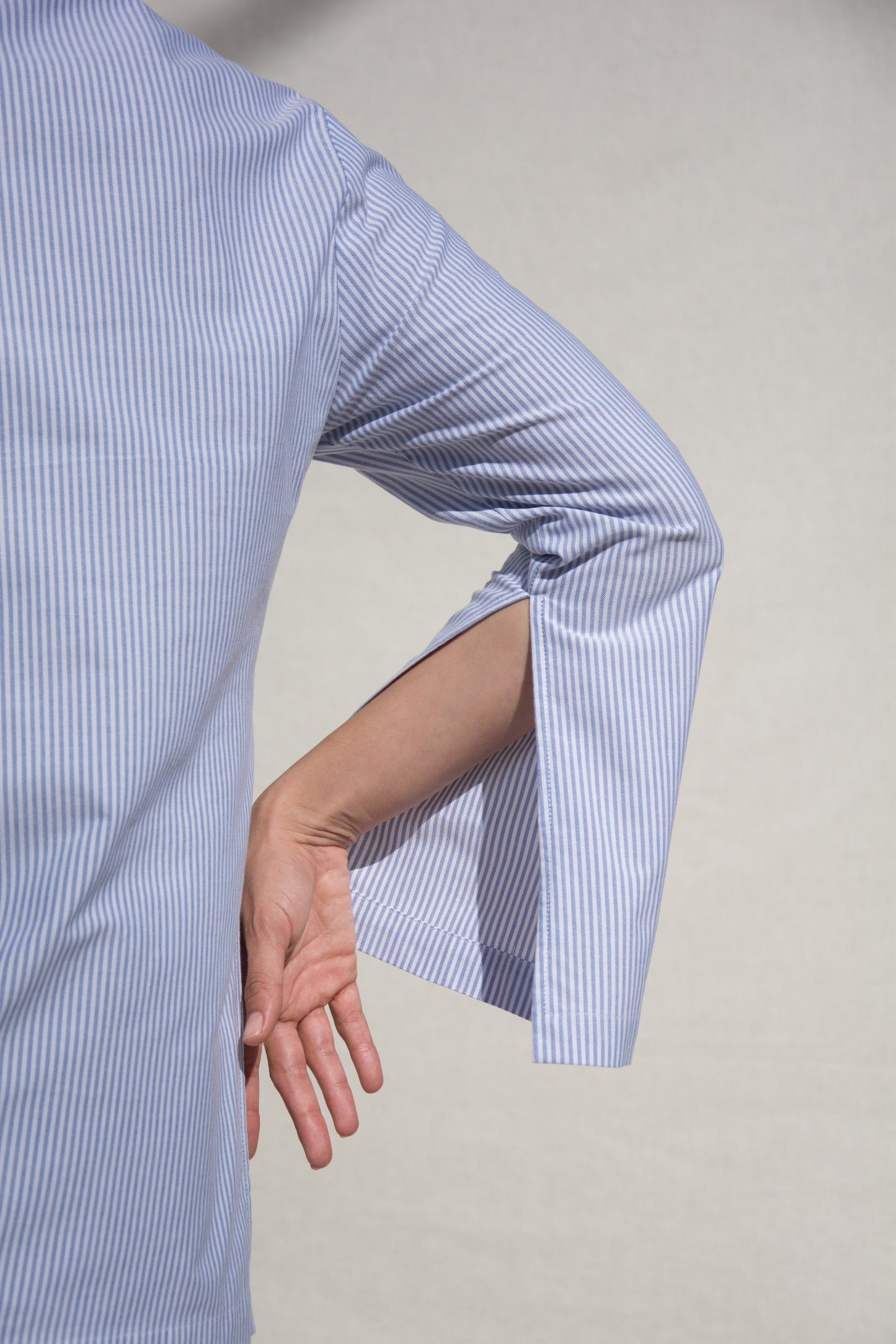 Detail image of woman's arm showing slit in sleeve. Indigo stripe cotton.